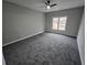 Large, carpeted bedroom with a ceiling fan, neutral walls, and a window with a view at 7910 Tintern Trce, Duluth, GA 30097