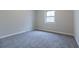 Bright bedroom featuring soft gray walls, plush carpeting, and a window offering natural light at 3436 Lake Monroe Rd, Douglasville, GA 30135