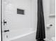Sleek bathtub with crisp white subway tile and recessed niche, accented by modern black hardware at 4529 Lakeview Dr, Powder Springs, GA 30127