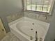 Bathroom features a soaking tub with tile surround and updated fixtures at 110 Orleans Blvd, Mcdonough, GA 30253