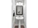 Powder room features pedestal sink, wood-look flooring, and framed mirror at 4575 Birch Way, Loganville, GA 30052