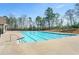 A large rectangular pool is surrounded by a concrete deck and a black fence and tall trees in the background at 4575 Birch Way, Loganville, GA 30052