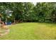 Large, grassy backyard featuring mature trees, and colorful outdoor chairs at 522 Knollwood Dr, Stockbridge, GA 30281
