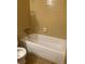 A bathtub and toilet in a basic bathroom with yellow tiling at 3315 Canterbury Trl, Rex, GA 30273