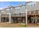 Rear view of townhomes with private decks, patios, and a shared grassy area for outdoor living and recreation at 1098 Caruso Dr, Buford, GA 30518