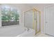 Bathroom featuring a soaking tub, gold-framed glass shower, and a window providing natural light at 2735 Princeton Trce, Cumming, GA 30041