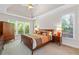Bedroom featuring large windows, tray ceilings, ceiling fan, carpeted floors, and an ensuite bathroom at 2735 Princeton Trce, Cumming, GA 30041