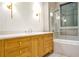 Bathroom featuring wood cabinets, marble countertops, and a glass shower and tub combo at 4550 Jolyn Pl, Sandy Springs, GA 30342