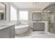 Bright bathroom featuring dual vanities, freestanding tub, large window, and marble floors at 210 Marjean Way, Alpharetta, GA 30009