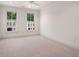 Bright bedroom featuring neutral carpet, trim and baseboards, ceiling fan, and two sunny windows overlooking outside buildings at 210 Marjean Way, Alpharetta, GA 30009