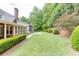 Expansive backyard with a stone fireplace, covered patio, lush lawn, and manicured landscaping surrounding the home at 7660 Dunvegan Close, Sandy Springs, GA 30350