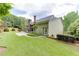 Exterior view showcasing the lush green lawn, patio area, and the home's architecture with an accent fireplace at 7660 Dunvegan Close, Sandy Springs, GA 30350