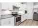 Eat-in kitchen features stainless steel appliances, white cabinets, granite counters, and wood-look flooring at 2646 Neighborhood S Walk, Villa Rica, GA 30180