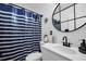 Modern bathroom featuring a sleek vanity, round mirror, and a blue and white striped shower curtain at 4682 Stonewall Tell Rd, College Park, GA 30349