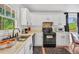 Bright kitchen featuring white cabinets, black appliances, and a large window with views at 4682 Stonewall Tell Rd, College Park, GA 30349