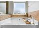Close up of bathtub showcasing travertine tile, a window, and a serene ambiance at 5655 Hedge Brook Dr, Cumming, GA 30028