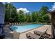 Community swimming pool surrounded by lounge chairs, lush greenery, and a clear blue sky at 5655 Hedge Brook Dr, Cumming, GA 30028