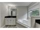 Well-lit primary bathroom featuring soaking tub with garden view, and granite countertop vanity at 179 Carter Rd, Auburn, GA 30011