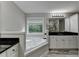 Well-lit primary bathroom featuring soaking tub, large window, and granite countertop vanity at 179 Carter Rd, Auburn, GA 30011