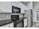 Modern kitchen features white cabinets, black appliances, granite countertops, and gray subway tile backsplash at 179 Carter Rd, Auburn, GA 30011