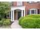 Charming front entrance with manicured bushes, white columns, a black door, and brick facade at 2310 Norbury Se Cv, Smyrna, GA 30080