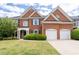 Traditional brick home with a two-car garage, manicured lawn, and mature landscaping at 2310 Norbury Se Cv, Smyrna, GA 30080