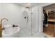 Modern bathroom featuring soaking tub, glass enclosed shower, white tile, and gold fixtures at 410 Wilkinson Se Dr, Atlanta, GA 30317