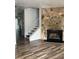 Bright living room featuring wood-look flooring, a stone fireplace, and a staircase with white railing at 458 Prince Of Wales, Stone Mountain, GA 30083