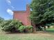 Side exterior view of a brick home with a deck, green lawn, and mature trees at 1301 Winesap Se Ct, Conyers, GA 30013