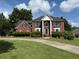 Traditional red brick home with large columns and a well-manicured front lawn under a bright sky at 1301 Winesap Se Ct, Conyers, GA 30013