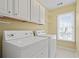 Dedicated laundry room with washer, dryer, upper cabinets, and a window at 1605 Pavillion Ridge Se Dr, Smyrna, GA 30080