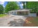 View of the home's facade with a carport and a paved driveway surrounded by lush landscaping at 1640 Fairburn Sw Rd, Atlanta, GA 30331