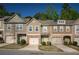 Charming townhomes showcasing varied color palettes, brick accents, and single-car garages under a clear blue sky at 1296 Taylor Way, Stone Mountain, GA 30083
