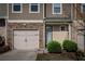 Close-up of a townhome facade showing a garage, front door, and stone detailing enhancing its curb appeal at 1296 Taylor Way, Stone Mountain, GA 30083