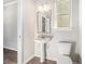 A simple bathroom features a pedestal sink, toilet, and mirror with a view into another room at 2349 Hanover Woods Rd, Lithonia, GA 30058