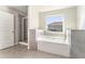 A bathroom featuring a soaking tub, a glass shower, and neutral tile flooring at 2349 Hanover Woods Rd, Lithonia, GA 30058