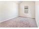An empty bedroom with neutral walls, carpet flooring, and a view of the outside at 2349 Hanover Woods Rd, Lithonia, GA 30058