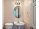 Well-lit powder room features pedestal sink, round mirror, and modern fixtures at 91 Davis Mill Ct, Lawrenceville, GA 30044