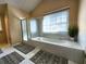 Bright bathroom featuring a garden tub with shower, tile flooring, and a window for natural light at 1225 Creek Laurel Dr, Lawrenceville, GA 30043