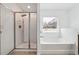 Bright bathroom featuring a glass shower and soaking tub under a window with privacy blinds at 4260 Hammond Bridge Dr, Suwanee, GA 30024