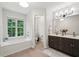 Bright bathroom featuring double vanity, tub under a window, and neutral flooring at 120 Park Bridge Ln, Roswell, GA 30075
