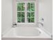 Close up of bathtub under a window with wooded view at 120 Park Bridge Ln, Roswell, GA 30075