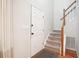 The entryway with a white door and stairwell features light gray walls, a patterned mat, and hardwood flooring at 120 Park Bridge Ln, Roswell, GA 30075