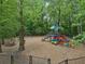 A playground featuring slides, a tower, and colorful ground features surrounded by trees and wood chips at 120 Park Bridge Ln, Roswell, GA 30075