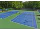 Close-up of the community's tennis courts with blue surface, green perimeter, and well-maintained nets ready for a match at 120 Park Bridge Ln, Roswell, GA 30075