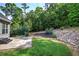A serene backyard featuring a stone patio, lush lawn, and decorative rock landscaping at 20 Spruce Ne St, White, GA 30184