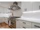 Close-up of a kitchen with white cabinets, quartz countertops, and stainless steel range and hood at 2729 Ridge Valley Nw Rd, Atlanta, GA 30327