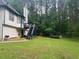 Exterior side of the home with elevated deck, with sprawling backyard with lots of trees at 5022 Cliff Top Dr, Loganville, GA 30052