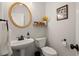 Elegant half bathroom featuring a pedestal sink, gold mirror, and stylish fixtures at 6790 Wolford Ct, Johns Creek, GA 30097