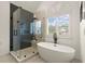 Modern bathroom featuring a glass-enclosed shower with herringbone tile and a freestanding tub by a window at 6790 Wolford Ct, Johns Creek, GA 30097